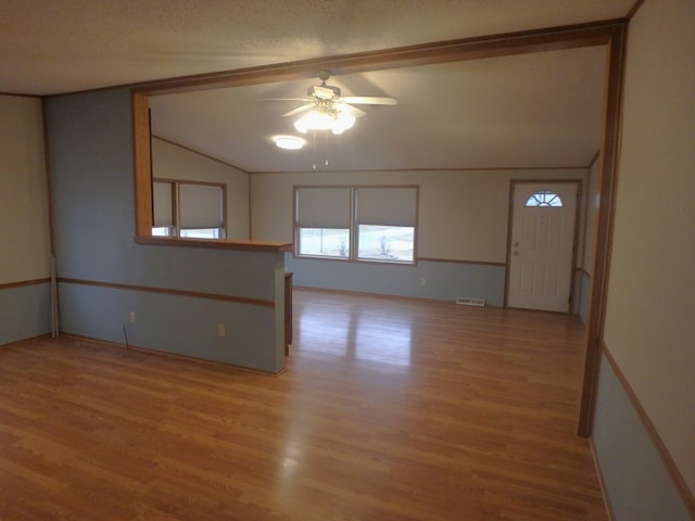 unfurnished room featuring lofted ceiling, a textured ceiling, a ceiling fan, visible vents, and light wood-style floors