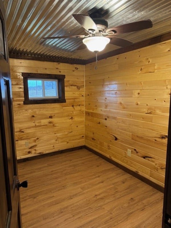 empty room featuring wooden walls, ceiling fan, wooden ceiling, and wood-type flooring