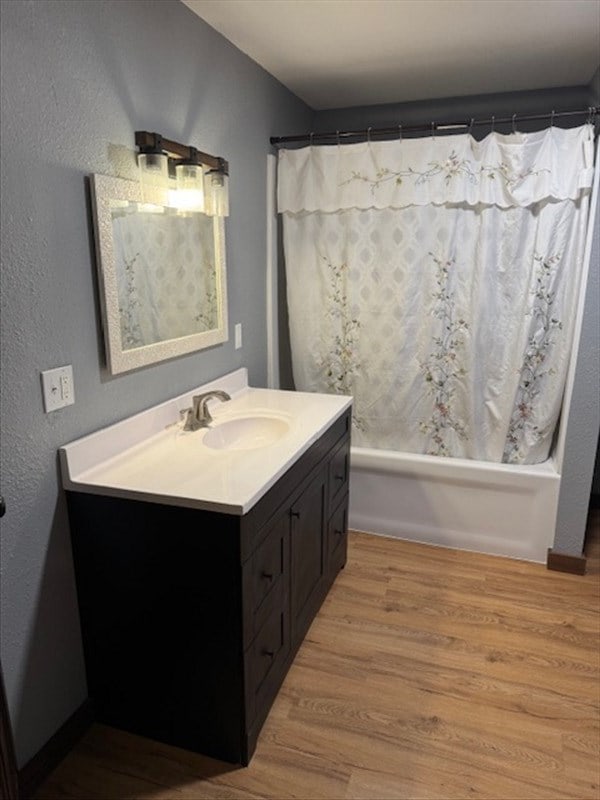 bathroom with hardwood / wood-style flooring, vanity, and shower / bathtub combination with curtain