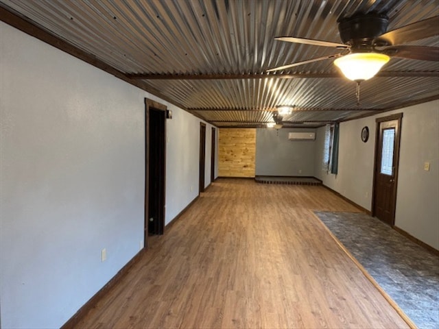 spare room with a wall unit AC, ceiling fan, and hardwood / wood-style flooring