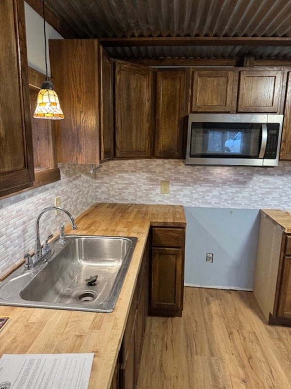 kitchen featuring decorative light fixtures, tasteful backsplash, butcher block counters, and sink