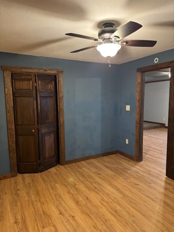 unfurnished room with ceiling fan, a textured ceiling, and light wood-type flooring