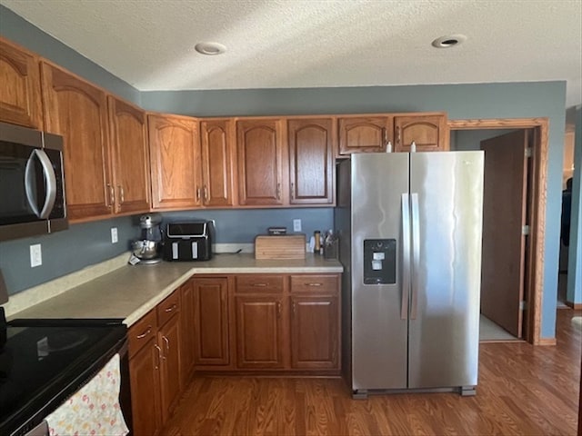 kitchen featuring a textured ceiling, dark hardwood / wood-style flooring, and stainless steel appliances