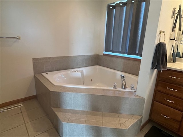 bathroom with tile patterned flooring, vanity, and tiled tub