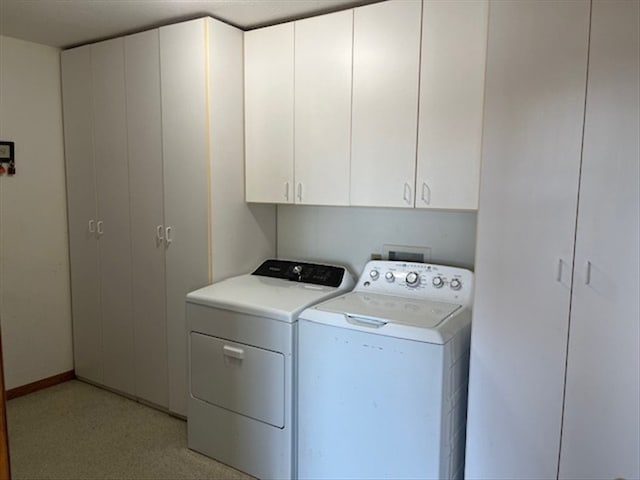 clothes washing area featuring washing machine and dryer and cabinets