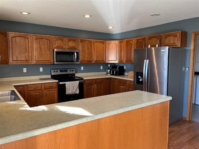 kitchen with kitchen peninsula, wood-type flooring, and appliances with stainless steel finishes