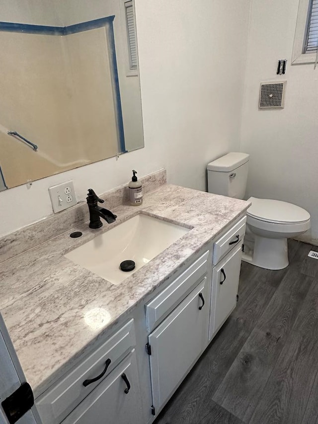 bathroom with wood-type flooring, vanity, and toilet