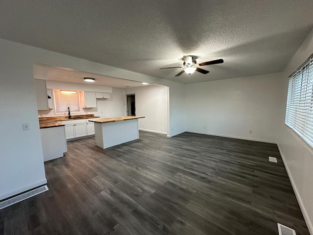 kitchen featuring white cabinetry, sink, dark hardwood / wood-style flooring, butcher block countertops, and a textured ceiling