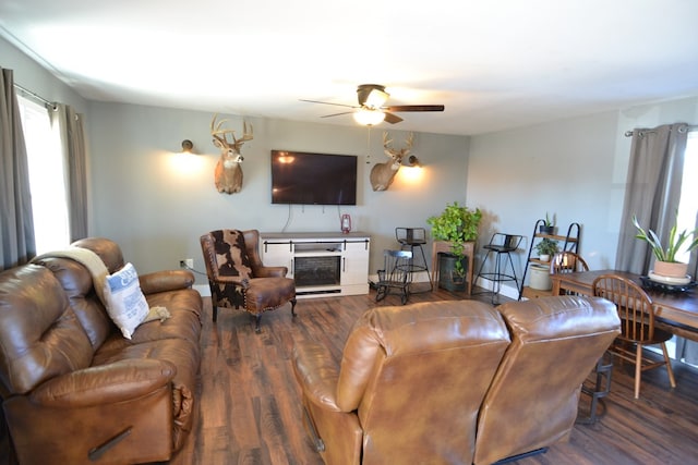 living room featuring ceiling fan, a fireplace, and dark hardwood / wood-style flooring