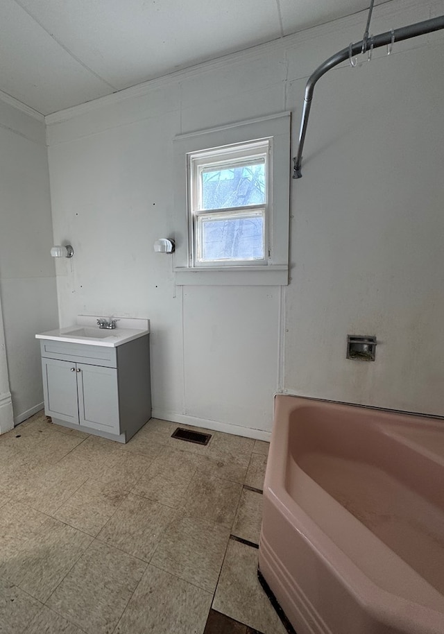 bathroom with a tub, visible vents, ornamental molding, and vanity