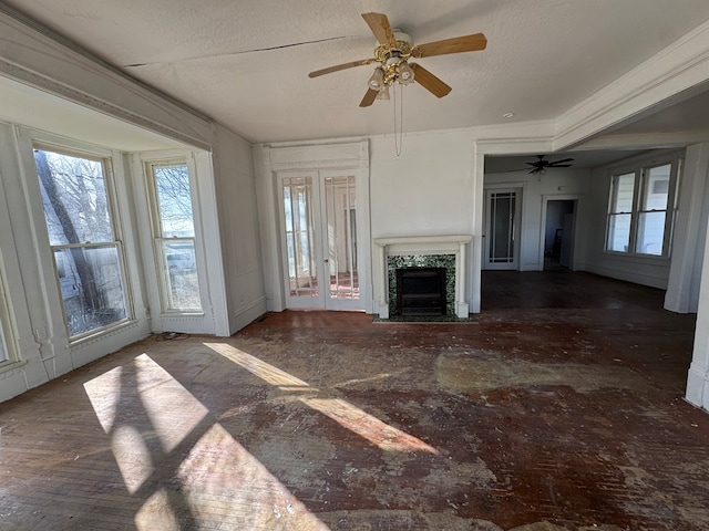 unfurnished living room with a fireplace with flush hearth, a textured ceiling, crown molding, and a ceiling fan