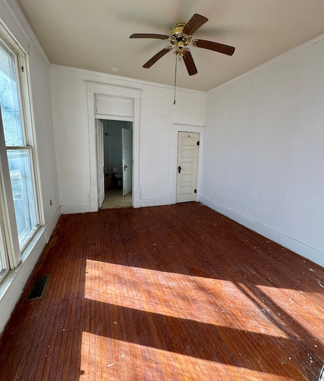 spare room with visible vents, wood-type flooring, baseboards, and crown molding