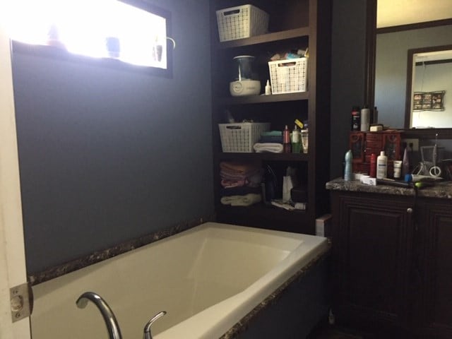 bathroom featuring a tub to relax in, built in features, and vanity