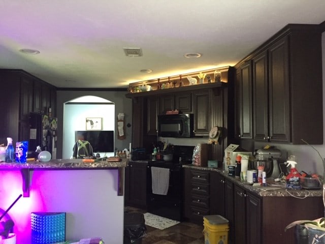 kitchen featuring black appliances, dark brown cabinets, and kitchen peninsula