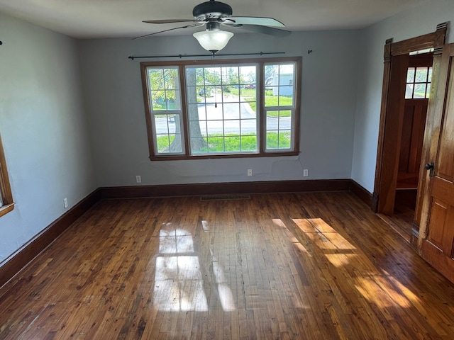 spare room with baseboards, a ceiling fan, and dark wood finished floors