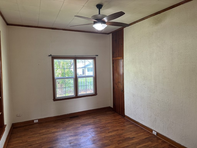 empty room featuring a ceiling fan, baseboards, dark wood-style floors, ornamental molding, and a textured wall