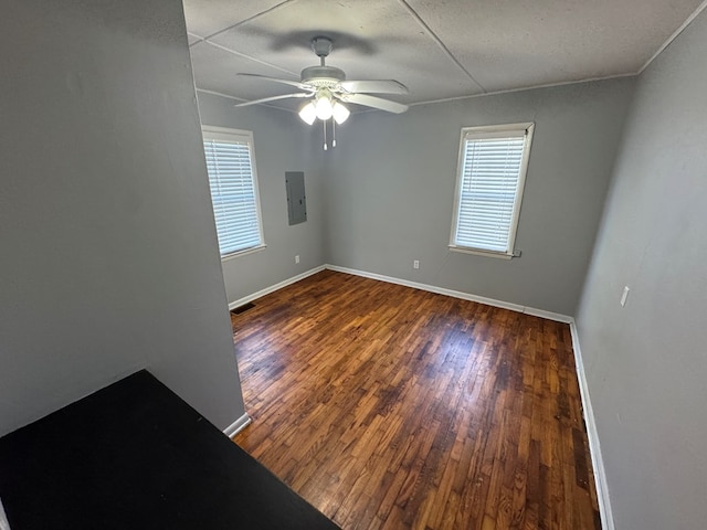empty room with baseboards, ceiling fan, electric panel, and wood finished floors