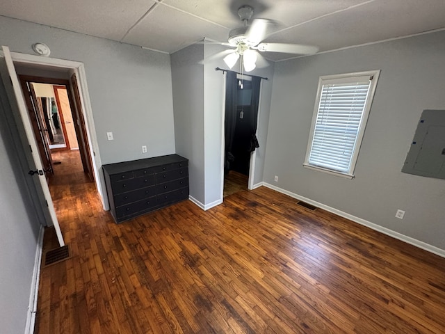 unfurnished bedroom featuring a ceiling fan, baseboards, dark wood-type flooring, visible vents, and electric panel