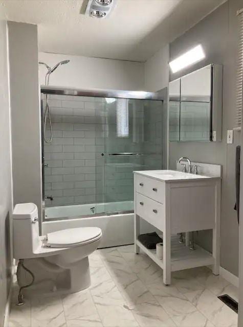 full bathroom featuring vanity, toilet, and bath / shower combo with glass door