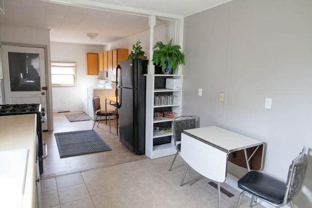 kitchen featuring black refrigerator, light tile patterned floors, and light brown cabinetry