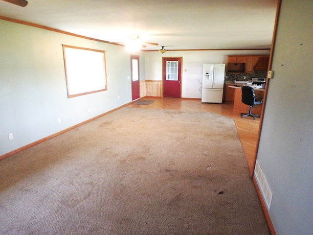 unfurnished living room featuring ceiling fan and crown molding