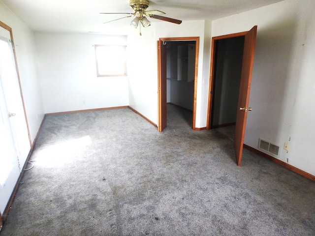 unfurnished bedroom featuring carpet, a closet, a spacious closet, and ceiling fan