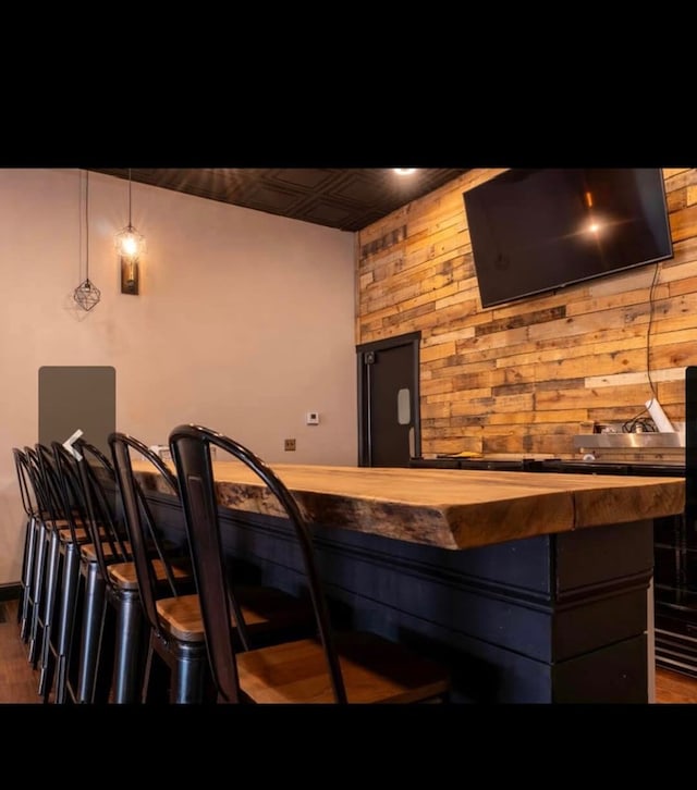 bar with wood counters, dark hardwood / wood-style floors, wooden walls, and decorative light fixtures