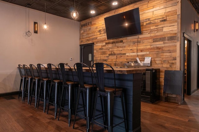 bar with dark hardwood / wood-style flooring and hanging light fixtures