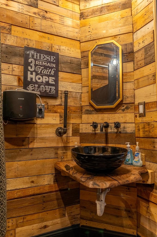 bathroom featuring sink and wood walls