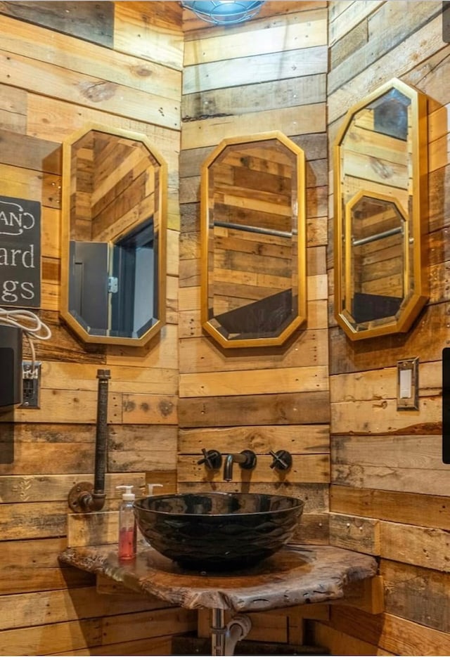 bathroom featuring wood walls and sink