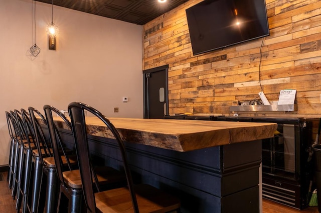 bar with wooden counters, wood walls, dark hardwood / wood-style floors, and hanging light fixtures