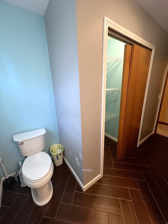 bathroom with toilet, baseboards, and parquet floors