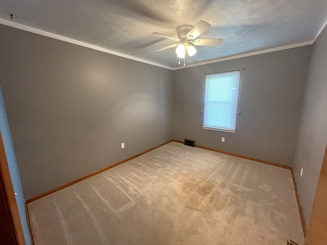 carpeted spare room featuring a ceiling fan, baseboards, and ornamental molding