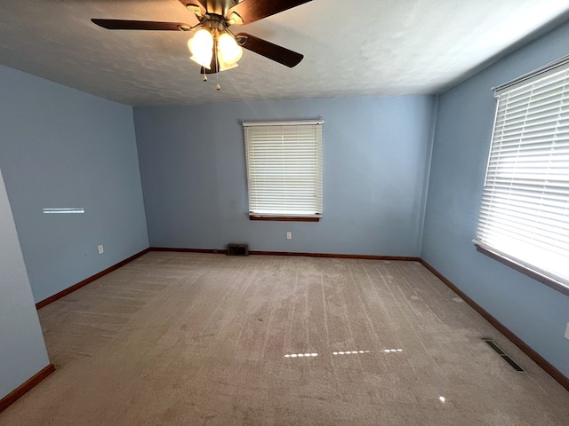 spare room featuring ceiling fan, carpet, and baseboards