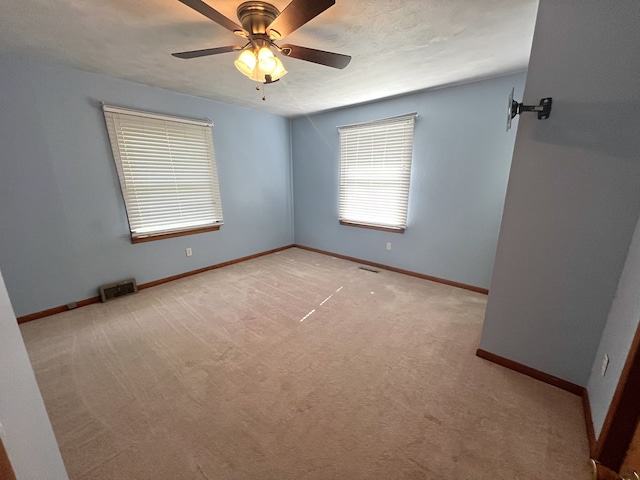 unfurnished room featuring light carpet, a ceiling fan, and baseboards