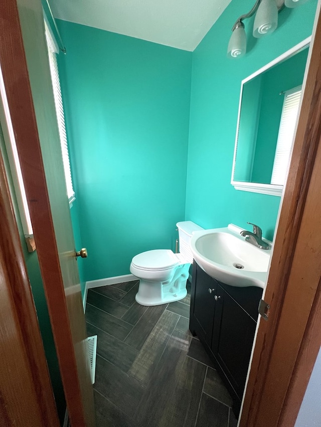bathroom with toilet, vanity, and baseboards