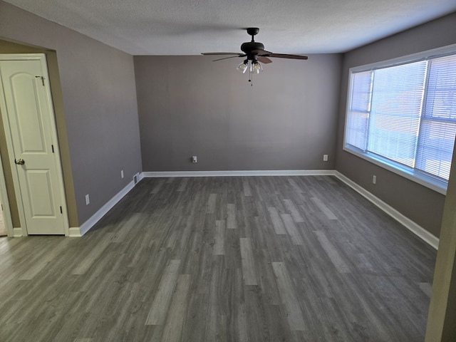 spare room featuring ceiling fan, a textured ceiling, baseboards, and dark wood-style flooring