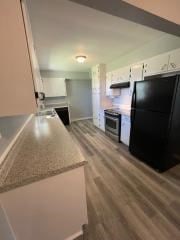 kitchen with white cabinets, wood finished floors, stainless steel range with electric cooktop, light countertops, and freestanding refrigerator