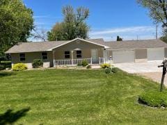 ranch-style house with a front lawn, an attached garage, concrete driveway, and a porch