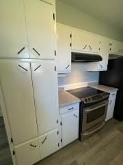 kitchen featuring stainless steel range with electric stovetop, under cabinet range hood, white cabinets, light countertops, and wood finished floors