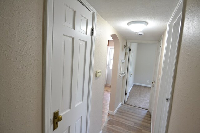 1415 E Patterson St, Kirksville, MO 63501 - hallway featuring arched walkways, a textured ceiling, light wood-style flooring, and a textured wall
