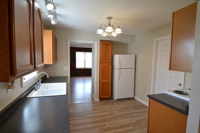 1415 E Patterson St, Kirksville, MO 63501 - kitchen with freestanding refrigerator, a chandelier, light wood-type flooring, brown cabinetry, and dark countertops