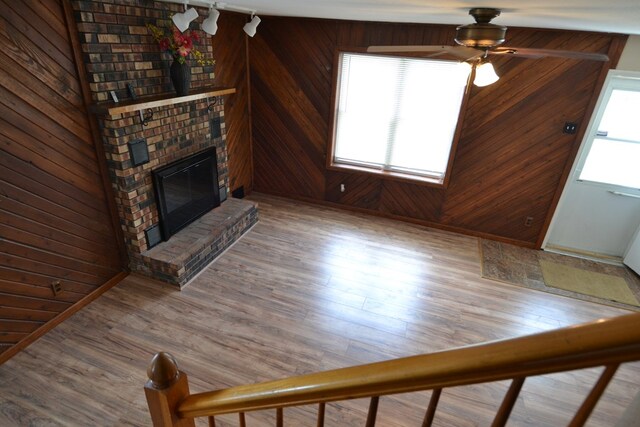 1415 E Patterson St, Kirksville, MO 63501 - unfurnished living room with wooden walls, a ceiling fan, a brick fireplace, and wood finished floors