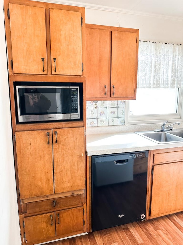 kitchen with dishwasher, sink, crown molding, and light wood-type flooring