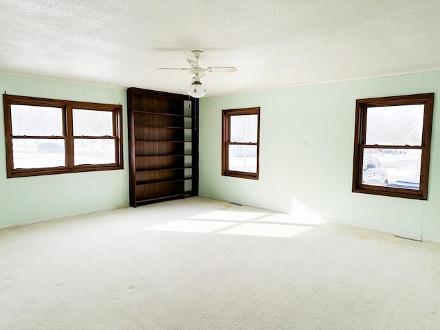 carpeted spare room featuring ceiling fan and a textured ceiling