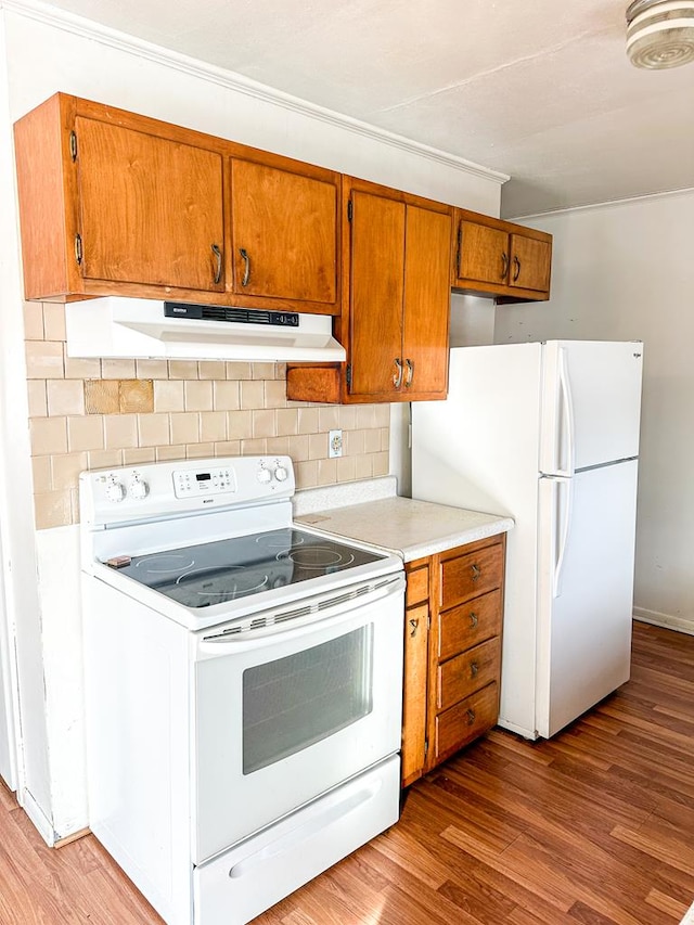 kitchen with white appliances, light hardwood / wood-style flooring, and decorative backsplash