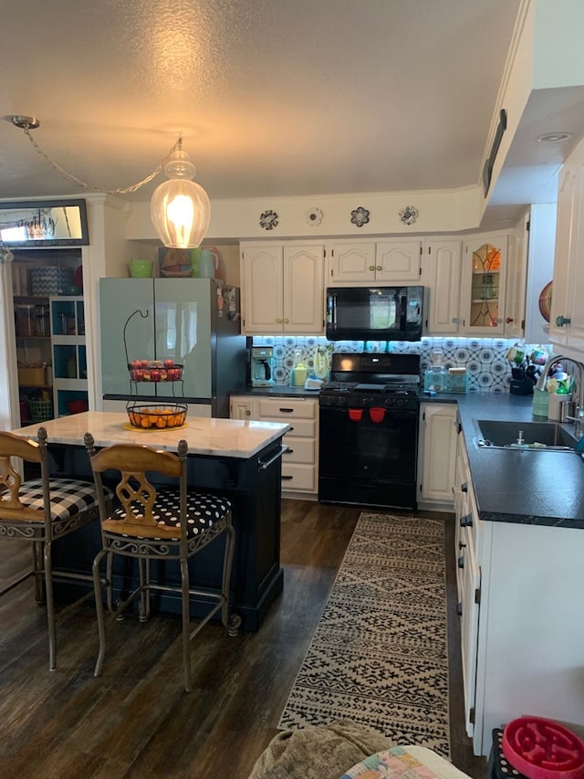 kitchen with a sink, dark wood-type flooring, black appliances, and white cabinetry