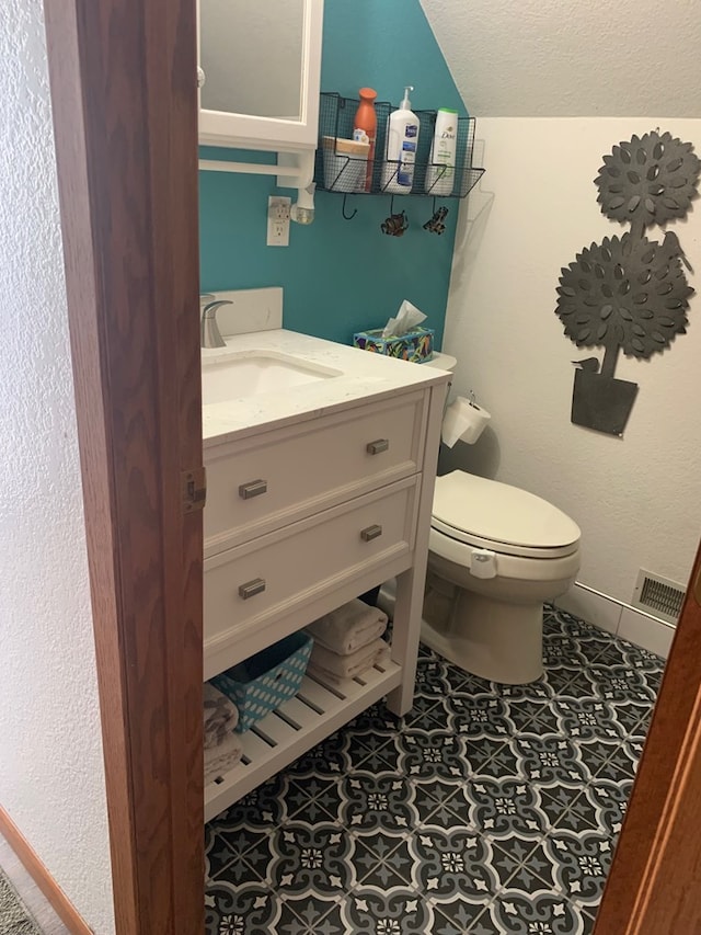 half bathroom with tile patterned flooring, visible vents, baseboards, toilet, and vanity