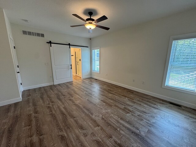 22585 State Highway K, Novinger, MO 63559 - unfurnished bedroom with a barn door, dark wood-type flooring, and a ceiling fan