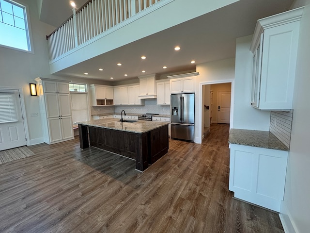 22585 State Highway K, Novinger, MO 63559 - kitchen featuring appliances with stainless steel finishes, tasteful backsplash, dark wood-style floors, stone counters, and a high ceiling